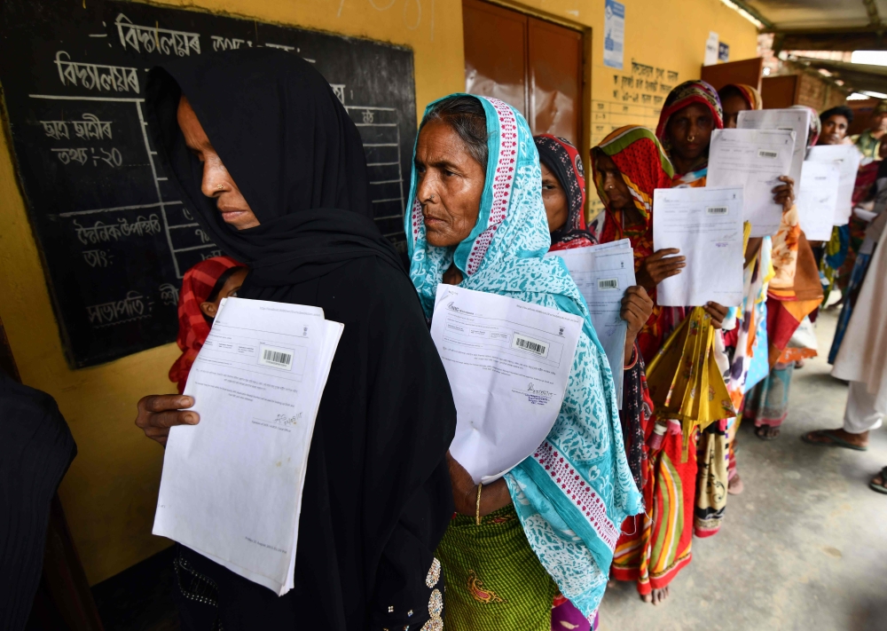 Residents hold their documents as they stand in a queue to check their names on the final list of National Register of Citizens (NRC) at a NRC Sewa Kendra (NSK) in Burgoan village in Morigoan district on July 30, 2018. (AFP / Biju BORO)