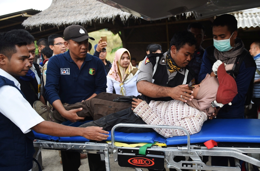 Rescue team members give treatment to a climber after walking down from Rinjani Mountain at Sembalun village in Lombok Timur, Indonesia, July 30, 2018. Antara Foto/Akbar Nugroho Gumay/via Reuters