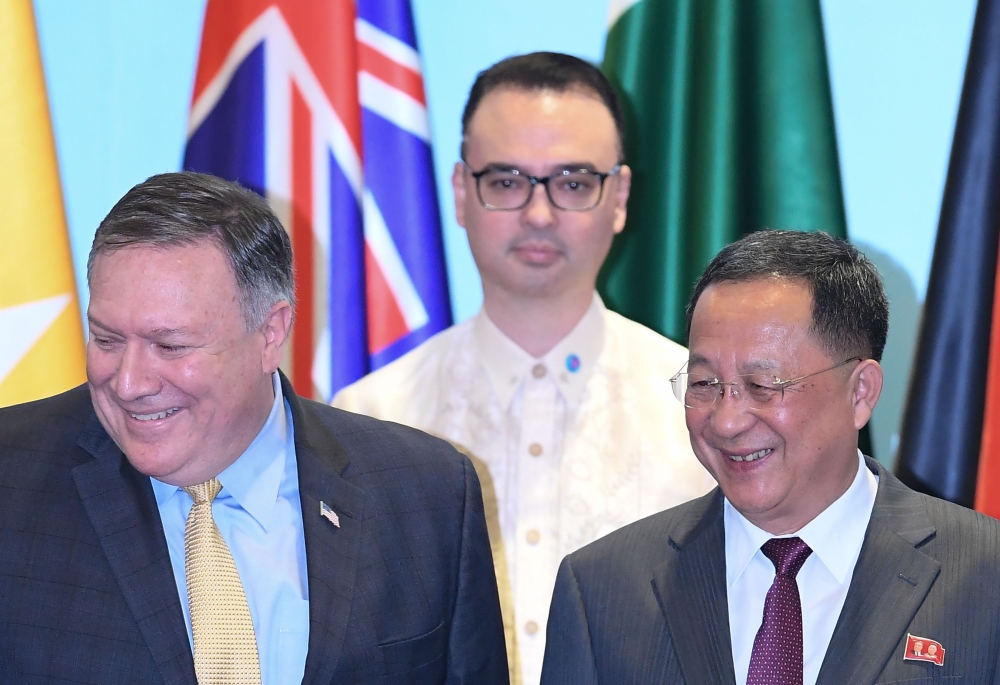 US Secretary of State Mike Pompeo (L) and North Korea's Foreign Minister Ri Yong Ho (R) smile as Philippine Foreign Secretary Alan Peter Cayetano (behind) looks on, as they arrive for a group photo at the ASEAN Regional Forum Retreat during the 51st Assoc