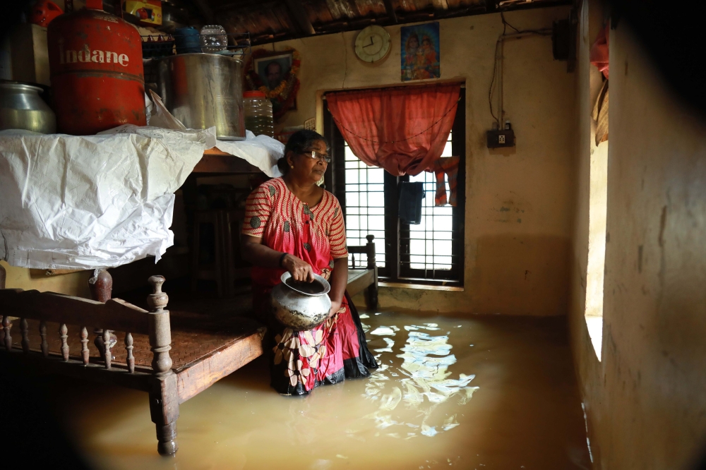 An Indian woman sits inside her houses immersed in flood waters in Ernakulam district of Kochi, in the Indian state of Kerala on August 10, 2018. AFP
 