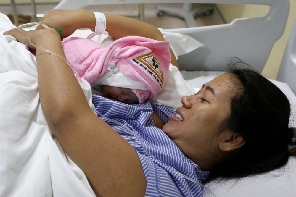 Pan Ei Mon, the wife of detained Reuters journalist Wa Lone, embraces her newborn baby girl Thet Htar Angel in her hospital room in Yangon on August 10, 2018. AFP /Ann WANG 