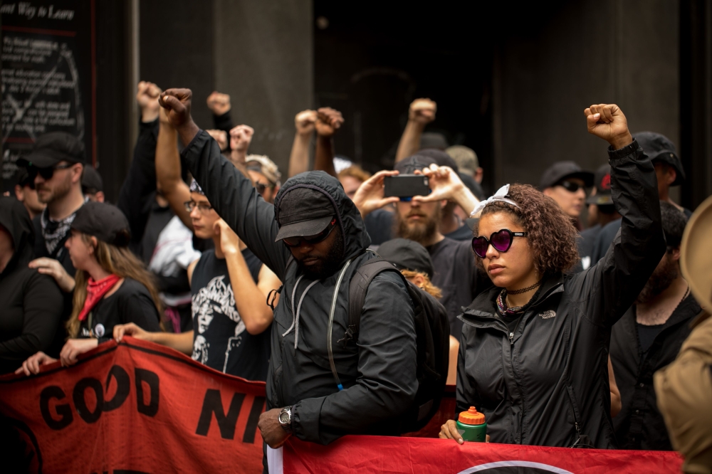 Members of ANTIFA get in formation after entering the security checkpoint required to enter the mall in downtown Charlottesville, Virginia, one-year after the violent white nationalist rally that left one person dead and dozens injured. / AFP / Logan Cyru