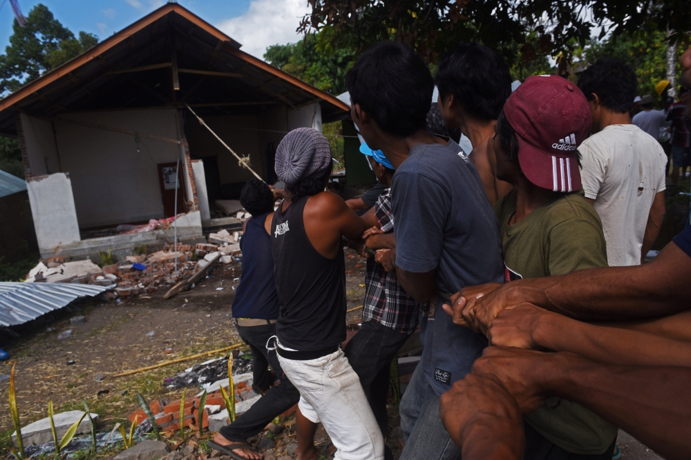 Residents pull down an earthquake damaged house in Kayangan, North lombok, Indonesia August 12, 2018. Antara Foto/Zabur Karuru/ via REUTERS