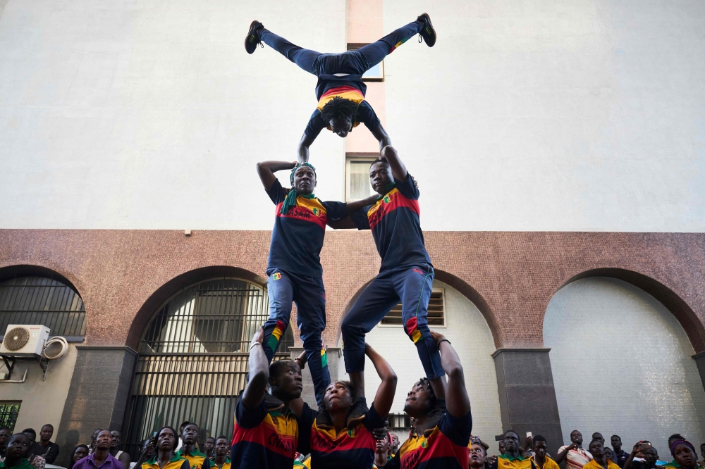 Acrobats perform outside the headquarters of Mali's incumbent president and candidate to his re-election in Bamako on August 13, 2018, in a show of support for the incumbent president one day after a presidential runoff vote. AFP / Michele Cattani
