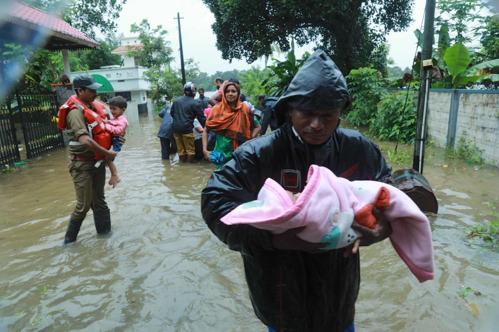 Fire and Rescue personnel evacuate local residents in an inflatable boat from a flooded area at Muppathadam near Eloor in Kochi's Ernakulam district, in the Indian state of Kerala on August 15, 2018. / AFP / - 