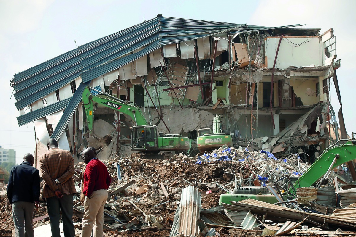 People watch as heavy machinery demolishes the Ukay Mall in Westlands, Nairobi, Kenya, August 14, 2018. Reuters/Baz Ratner 
