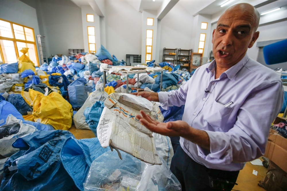 Ramadan Ghazawi, a Palestinian official at the central international exchange post office in the West Bank city of Jericho, holds up a damaged parcel, one of many items of previously undelivered mail dating as far back as 2010 which has been withheld by I