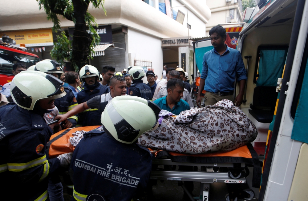 Firefighters carry the body of a victim killed in a fire at a residential building in Mumbai, India, August 22, 2018. REUTERS/Francis Mascarenhas