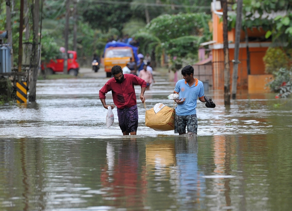  Indian men carry food and water aid distributed to those stranded by floods in Pandanad in Alappuzha District in the south Indian state of Kerala on August 21, 2018. (AFP / MANJUNATH KIRAN)
