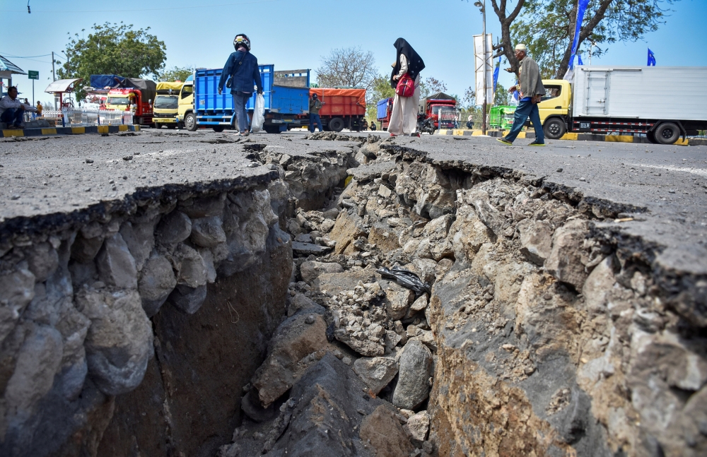 FILE PHOTO: People walk near a road damaged by earthquake at Kayangan Port in Lombok, Indonesia August 20, 2018. Antara Foto/Ahmad Subaidi
