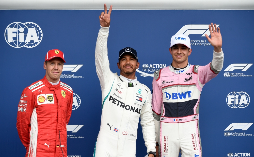 Mercedes' British driver Lewis Hamilton (C) celebrates winning the pole position next to second placed Ferrari's German driver Sebastian Vettel (L) and third placed Force India's French driver Esteban Ocon (R) after the qualifying session at the Spa-Franc