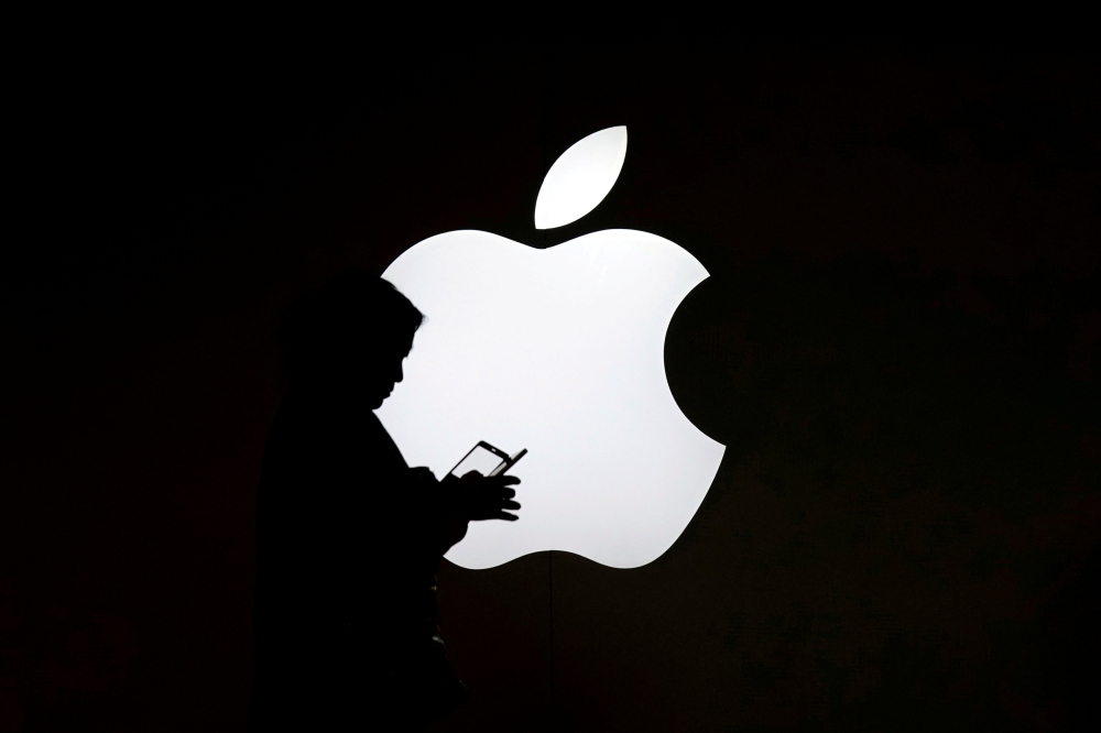 A woman looks at the screen of her mobile phone in front of an Apple logo outside its store in Shanghai, China July 30, 2017. (REUTERS/Aly Song/File Photo)