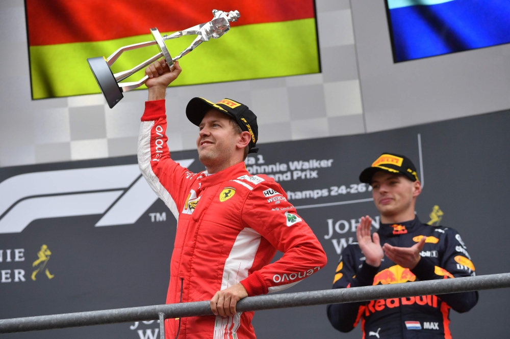 Winner Ferrari's German driver Sebastian Vettel (L) holds his trophy as he celebrates next to third placed Red Bull Racing's Dutch driver Max Verstappen on the podium after the Belgian Formula One Grand Prix at the Spa-Francorchamps circuit in Spa on Augu