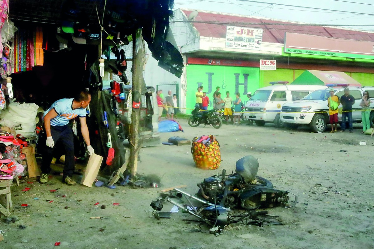 A police investigator (L) gathers evidence at the site of a bomb blast in Isulan town on the southern island of Mindanao on Augiust 29, 2018. AFP
