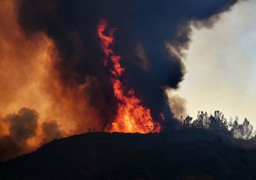 (FILES) In this file photo taken on August 3, 2018 flames estimated by firefighters to be 60-80 metres in height (200-260 feet), engulf a ridge as the River fire again threatens the town of Lakeport, California.  AFP / Mark Ralston 