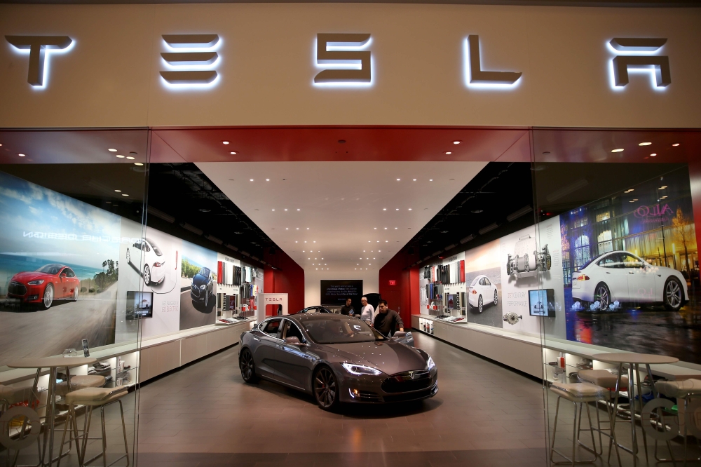 In this file photo taken on February 19, 2014, people look at a Tesla Motors vehicle on the showroom floor at the Dadeland Mall in Miami, Florida.  AFP / Getty Images North America / Joe Raedle 
