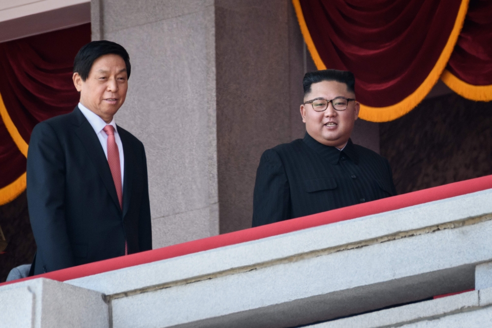 North Korea's leader Kim Jong Un (C) walks with China's Chairman of the Standing Committee of the National People's Congress Li Zhanshu (L) on a balcony of the Grand People's House on Kim Il Sung square following a military parade and mass rally in Pyongy