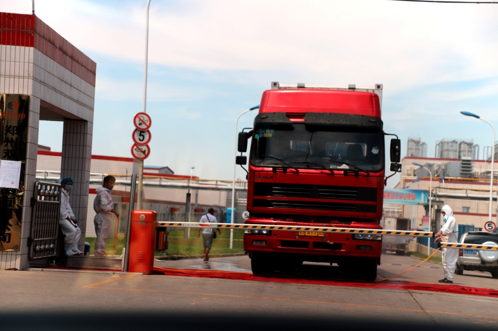 File photo of workers in protective suits are seen by a truck at a plant of pork processor Henan Shuanghui Investment & Development, a subsidiary of WH Group, following a discovery of pigs infected by the African swine fever (ASF), in Zhengzhou, Henan Aug