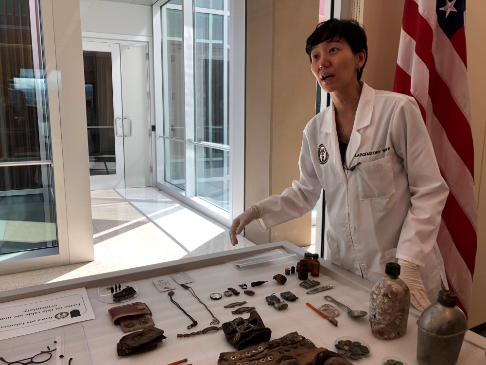 Jennie Jin, a forensic anthropologist who leads the Korea War Project at the Defense POW/MIA Accounting Agency (DPAA), shows some of the objects that accompanied the human remains handed over by North Korea, including a wallet, buttons and canteens, at Jo