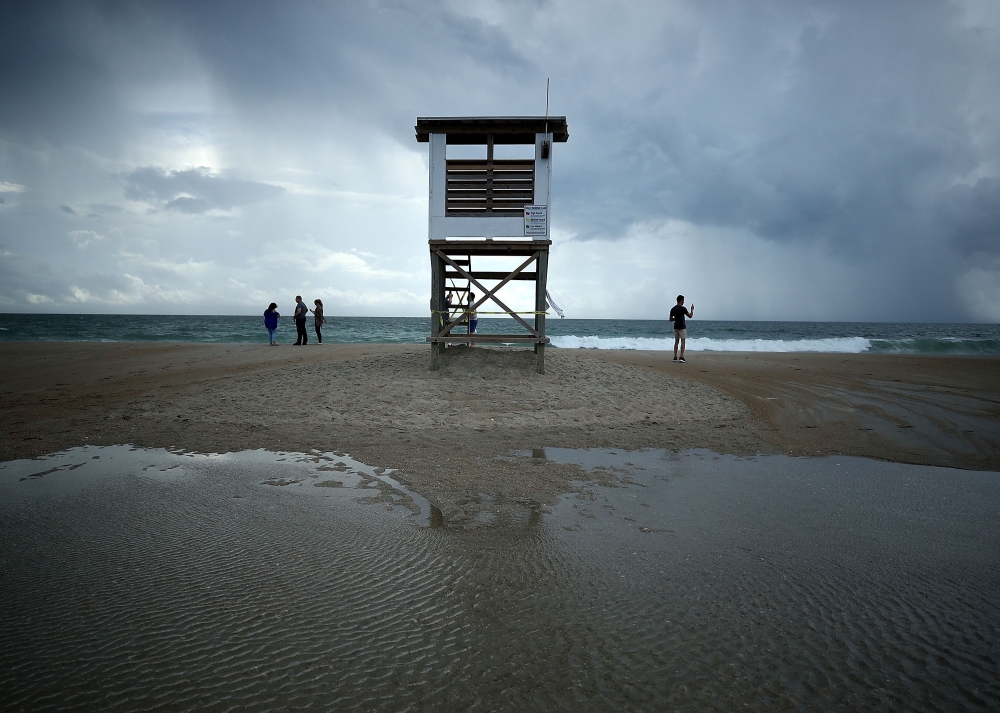 People stand near a lifeguard stand as Hurricane Florence approaches, on September 11, 2018 in Wrightsville Beach, United States. Mark Wilson/AFP