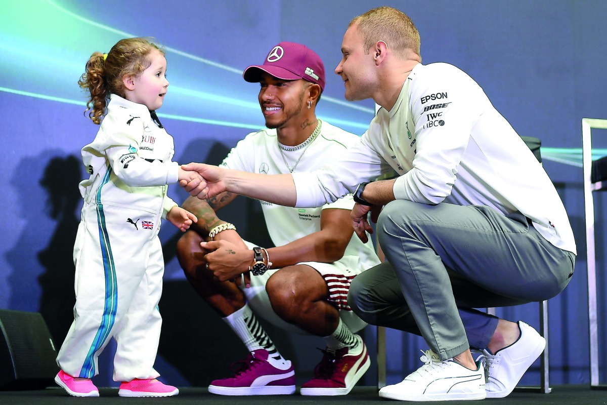 Mercedes' British driver Lewis Hamilton (C) and Mercedes' Finnish driver Valtteri Bottas speak with three-year-old fan Leila during a 'meet and greet' event at a shopping mall ahead of the Singapore Formula One Grand Prix in Singapore on September 13, 201