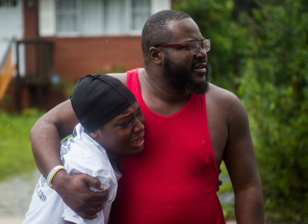 A father and daughter learn that friends were injured in a house that a tree fell on during landfall of Hurricane Florence, in Wilmington, North Carolina on September 14, 2018.  AFP / Andrew Caballero-Reynolds 