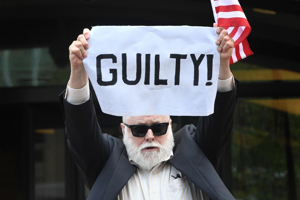 A protester holds a sign outside the US Courthouse in Alexandria, Virginia, on the fourth day in fraud case against former Trump campaign manager Paul Manafort on August 21, 2018. AFP / Jim Watson 