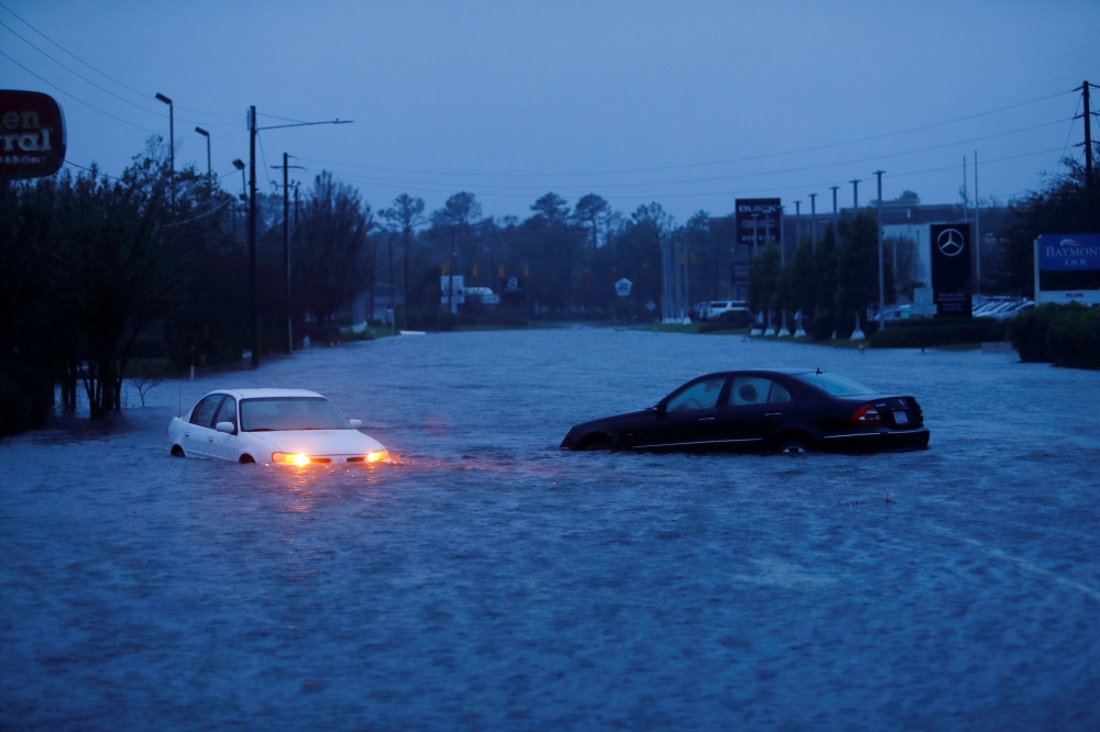 An abandoned car's hazard lights continue to flash as it sits submerged in a rising flood waters during pre-dawn hours after Hurricane Florence struck in Wilmington, North Carolina, U.S., September 15, 2018. REUTERS/Jonathan Drake
