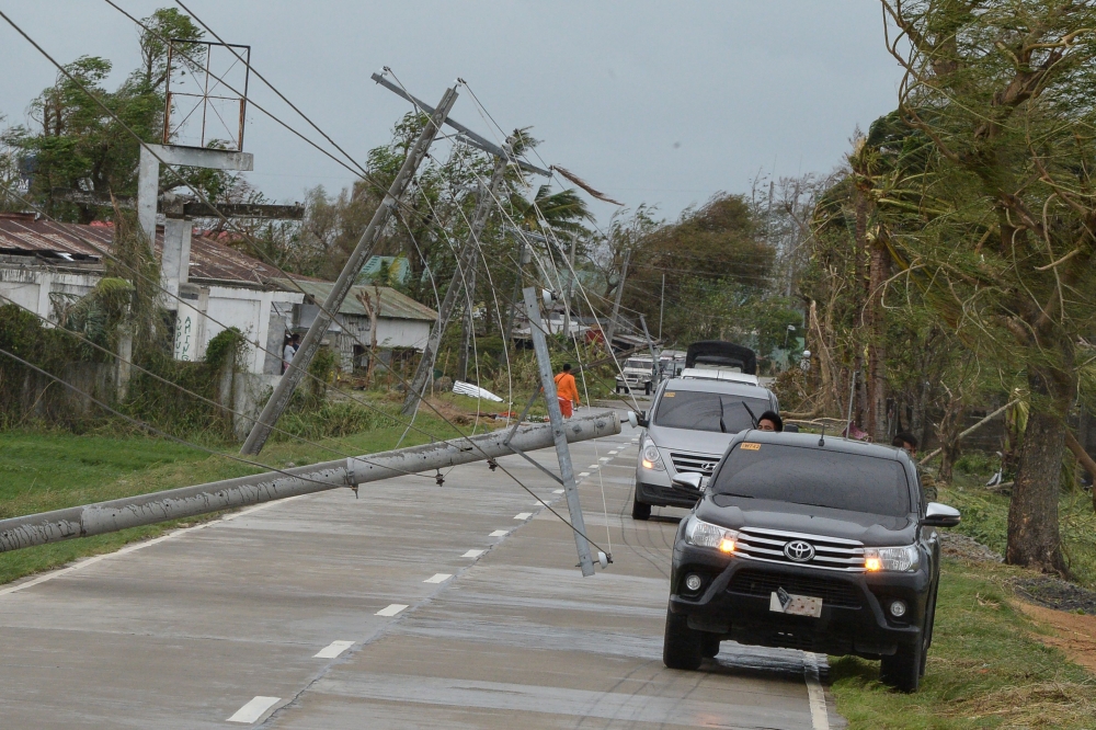 Vehicles commute past electric posts toppled by strong winds from Super Typhoon Mangkhut in Baggao, Cagayan province on September 15, 2018.  AFP / TED ALJIBE
