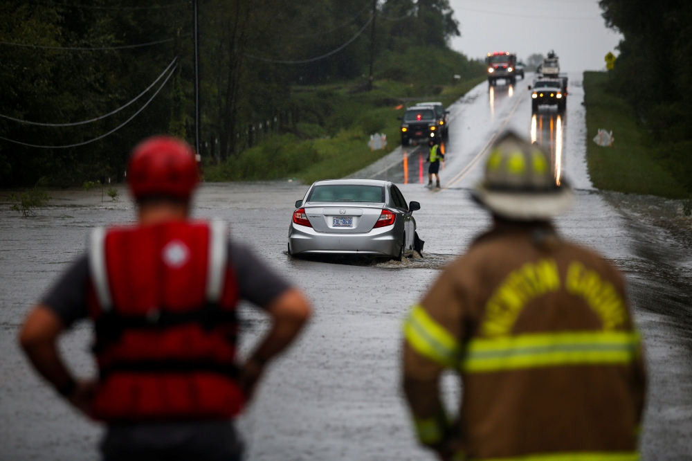 A car is stalled in flowing water, as first responders and firefighters try to check for people inside, during the pass of Hurricane Florence in the town of Clinton, North Carolina, U.S., September 15, 2018. REUTERS/Eduardo Munoz