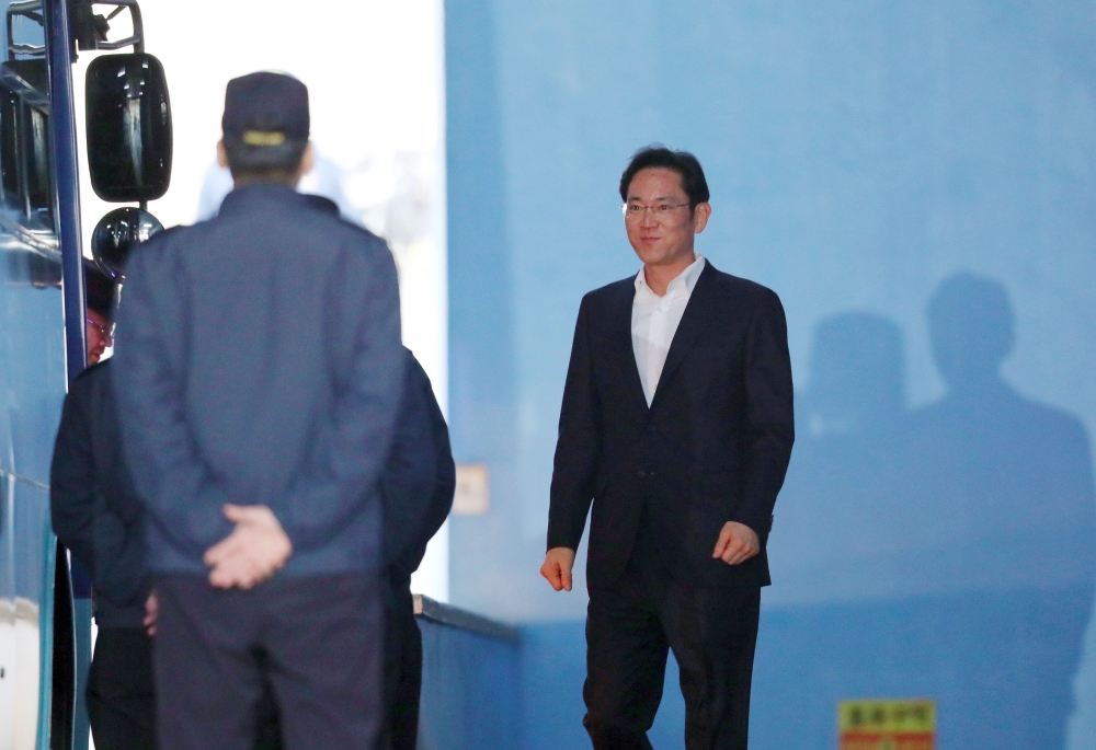 File photo of Samsung heir Lee Jae-Yong (R) walks out from a court in Seoul on February 5, 2018, after an appellate court handed him a suspended sentence. / AFP / Dong-A Ilbo / 