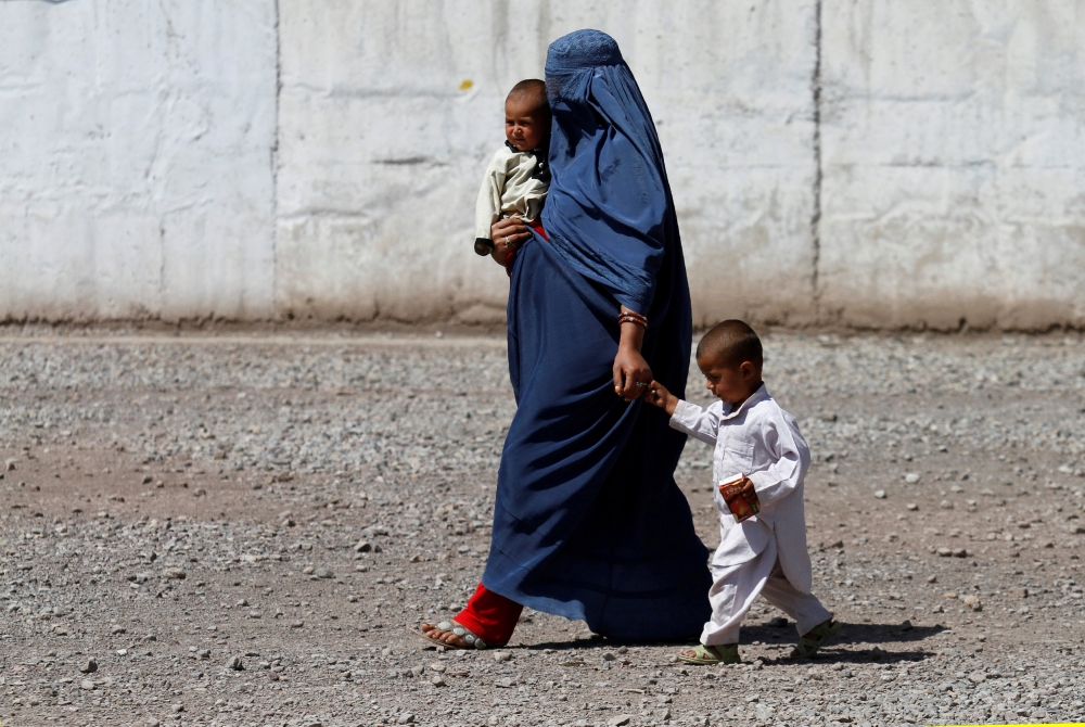 FILE PHOTO: An Afghan refugee woman arrives with her children to be repatriated to Afghanistan, at the United Nations High Commissioner for Refugees (UNHCR) office on the outskirts of Peshawar, Pakistan April 3, 2017. REUTERS/Fayaz Aziz