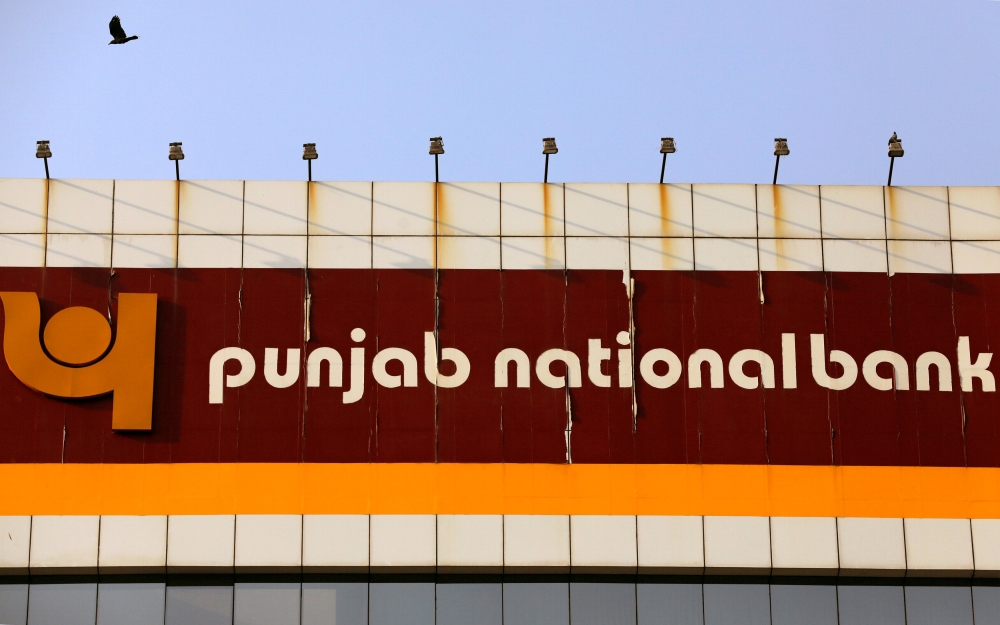 FILE PHOTO: A bird flies past the logo of Punjab National Bank installed on the facade of its office in Mumbai, India February 21, 2018. REUTERS/Danish Siddiqui/File Photo