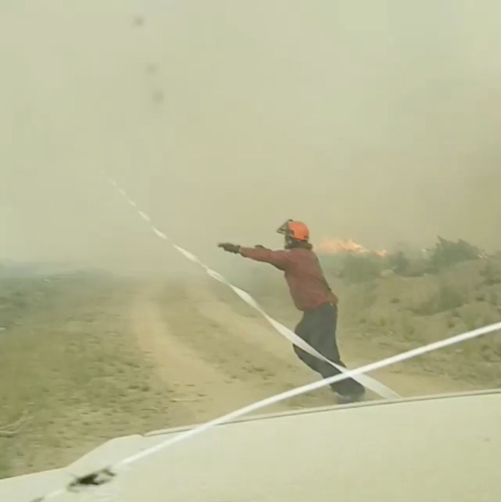 Firefighters try to pull a hose caught in a fire tornado in Vanderhoof British Columbia Canada in this still image taken from video August 19 2018. Instagram @MAR.LOWSKY/via Reuters 