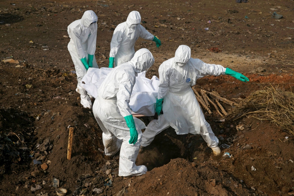 Health workers carry the body of a suspected Ebola victim for burial at a cemetery in Freetown, Sierra Leone, December 21, 2014. Reuters/Baz Ratner