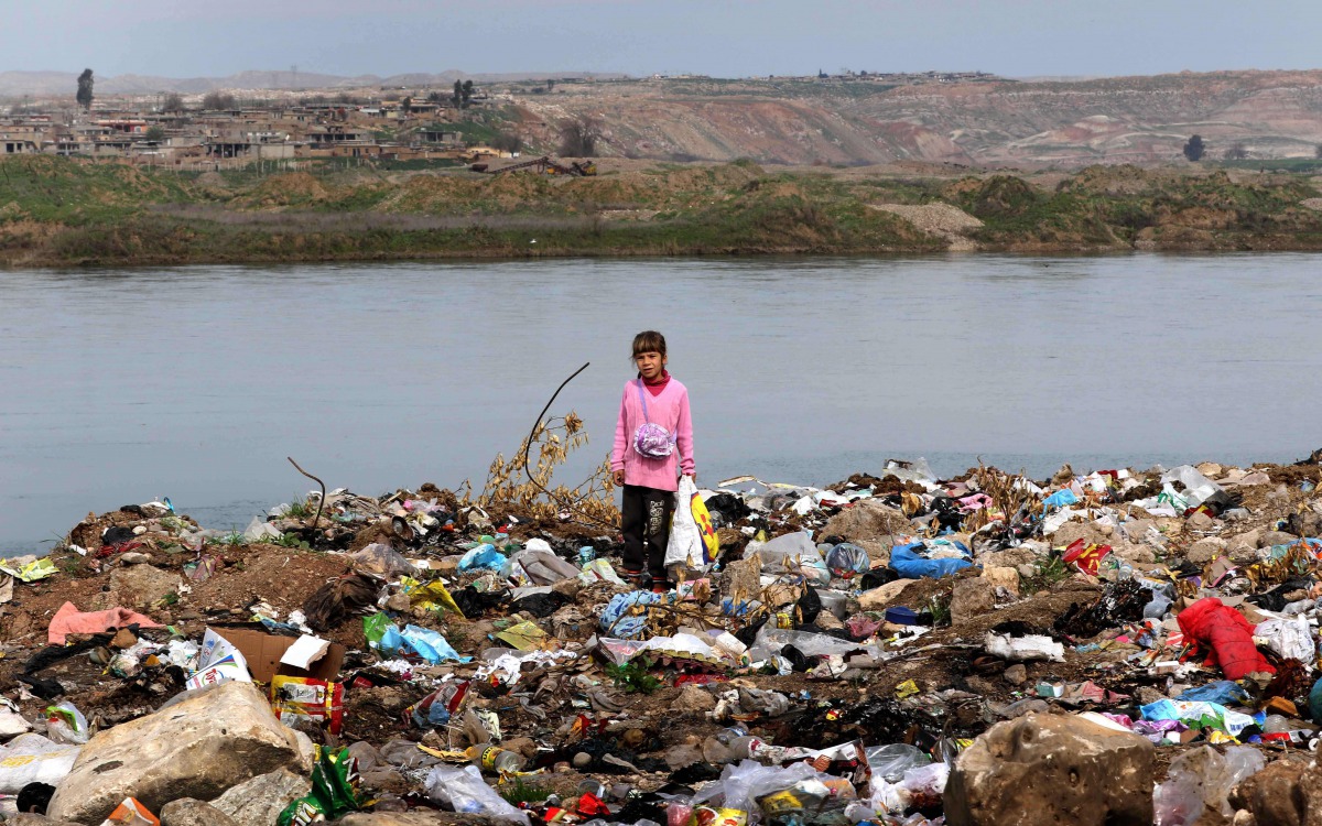 An Iraqi girl stands amid garbage on the banks of the Tigris River in the village of Wana, some 10 kms south of the Mosul Dam near the city of Mosul on March 3, 2016. AFP/Safin Hamed