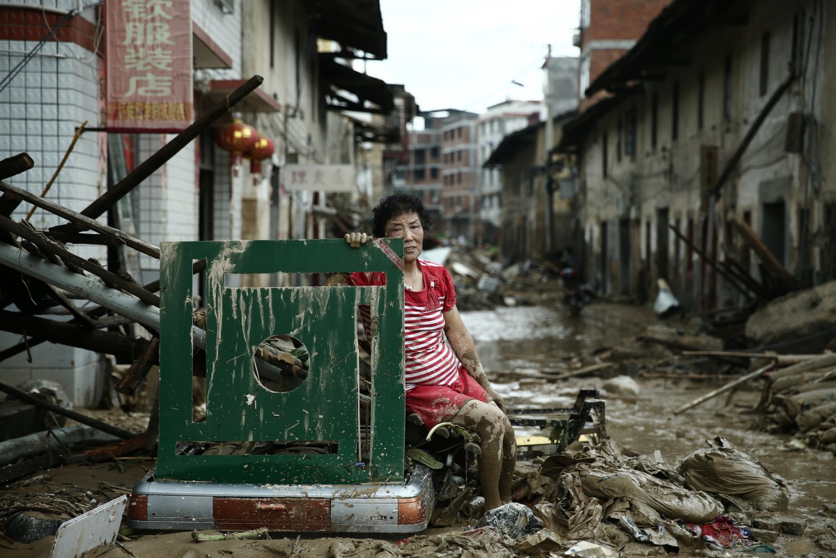 A woman sits on the ruins after typhoon Nepartak swept through Minqing county, Fujian province, China, July 10, 2016. (Reuters) 