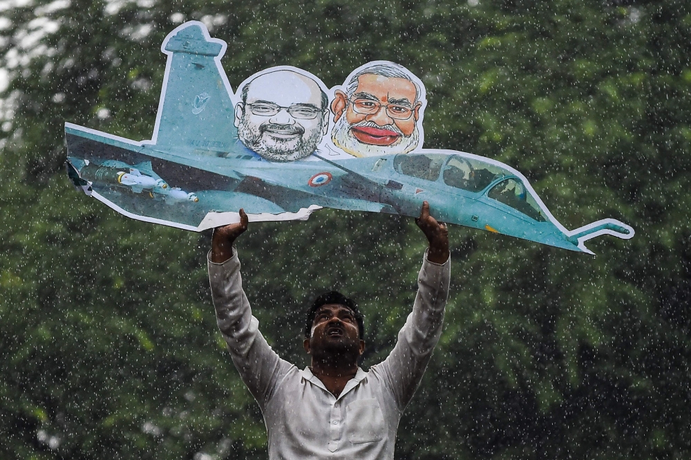 A supporter of the Indian Youth Congress holds a model of a Rafale fighter jet as he gets detained by Indian police during a protest in New Delhi on September 22, 2018. AFP / CHANDAN KHANNA