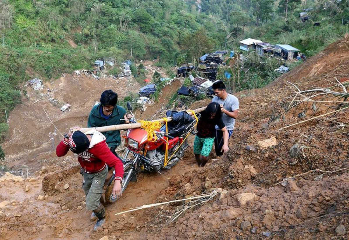 Residents carry a motorcycle as they hike on a road eroded by a landslide caused by Typhoon Mangkhut at a small-scale mining camp in Itogon, Benguet, in the Philippines, September 19, 2018. Reuters/Harlington Palangchao