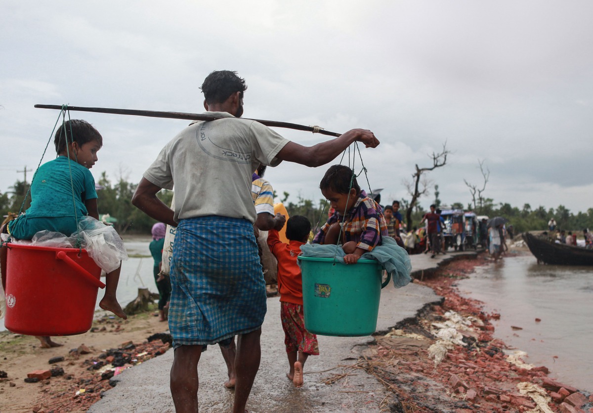A Rohingya refugee carries two children in buckets as they arrive in Bangladesh at Shah Porir Dwip in Teknaf on September 9, 2017, as they flee violence in neighbouring Myanmar (AFP/Emrul Kamal) 