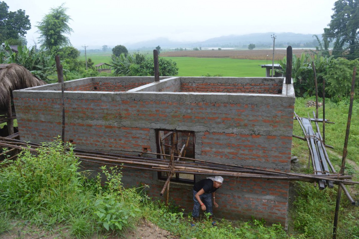 Kanchhi Rai cleans up the grass around her recently-erected home in the village of Raigaun, Nepal, August 5, 2018. Thomson Reuters Foundation/Arun Karki