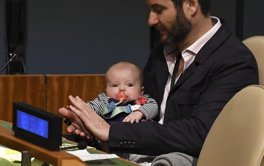 Clarke Gayford (C) claps holding his daughter Neve Te Aroha Ardern Gayford, as his partner Jacinda Ardern, Prime Minister of New Zealand speaks during the Nelson Mandela Peace Summit September 24, 2018 in New York. AFP / Don EMMERT 