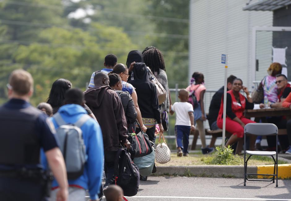 FILE PHOTO: A group of asylum seekers wait to be processed after being escorted from their tent encampment to the Canada Border Services in Lacolle, Quebec, Canada August 11, 2017. REUTERS/Christinne Muschi
