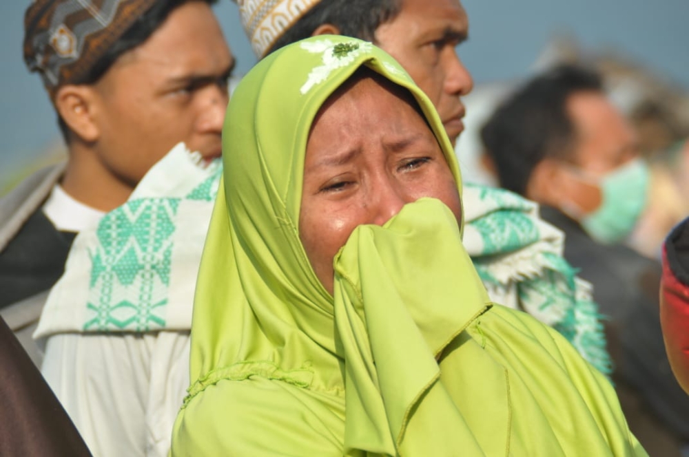 A woman cries as people look at the damages after an earthquake and a tsunami hit Palu, on Sulawesi island on September 29, 2018. AFP / MUHAMMAD RIFKI