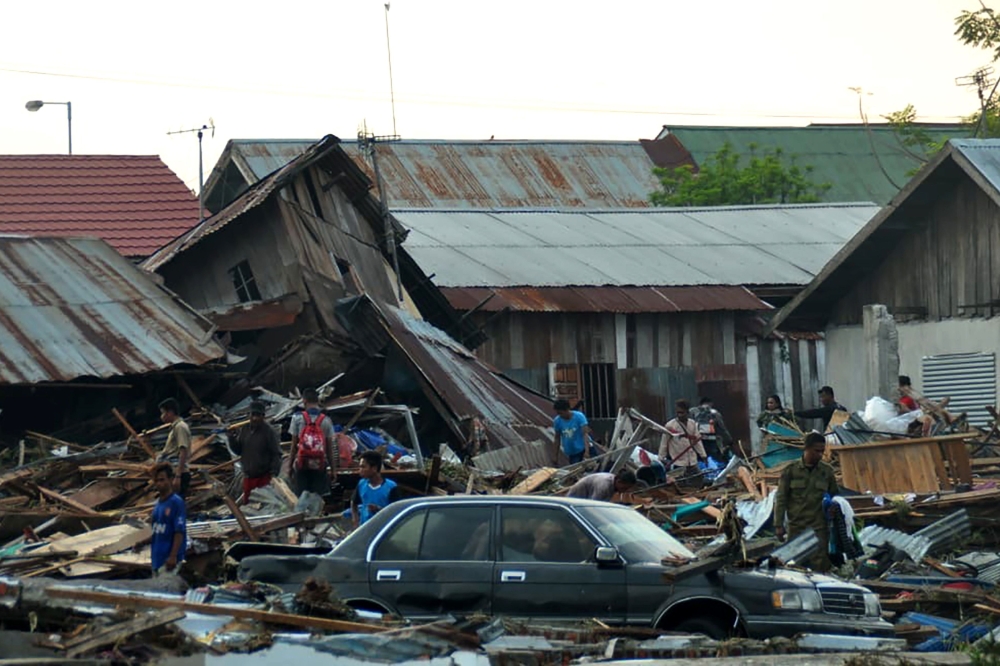 Residents trying to salvage belongings from their homes which collapsed after an earthquake and tsunami hit Palu on Sulawesi island on September 29, 2018.   AFP / MUHAMMAD RIFKI
