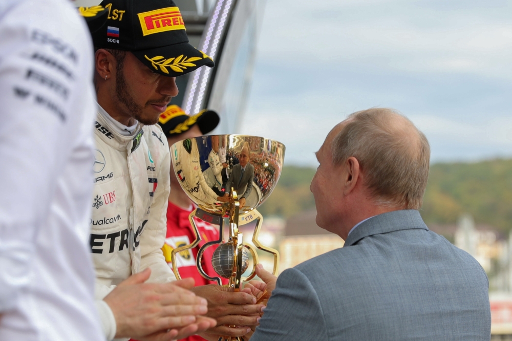 Russian President Vladimir Putin congratulates winner Mercedes' British driver Lewis Hamilton during the podium ceremony for the Formula One Russian Grand Prix at the Sochi Autodrom circuit in Sochi on September 30, 2018. / AFP / SPUTNIK / Mikhail KLIMENT