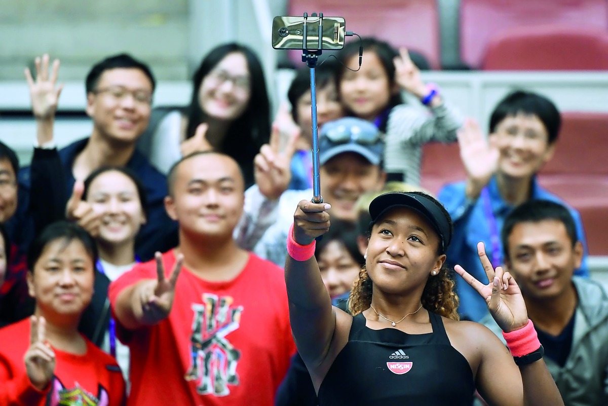 Naomi Osaka of Japan poses with fans after winning her women's singles third round match against Julia Goerges of Germany at the China Open tennis tournament in Beijing on October 4, 2018. AFP / Greg Baker

