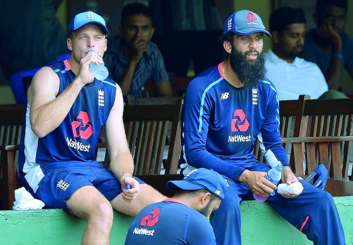England cricketers Jos Buttler (L) and Moeen Ali take a break while watching other players during a practice session at the P. Sara Oval Cricket Stadium in Colombo on October 4, 2018.  AFP / Lakruwan Wanniarachchi