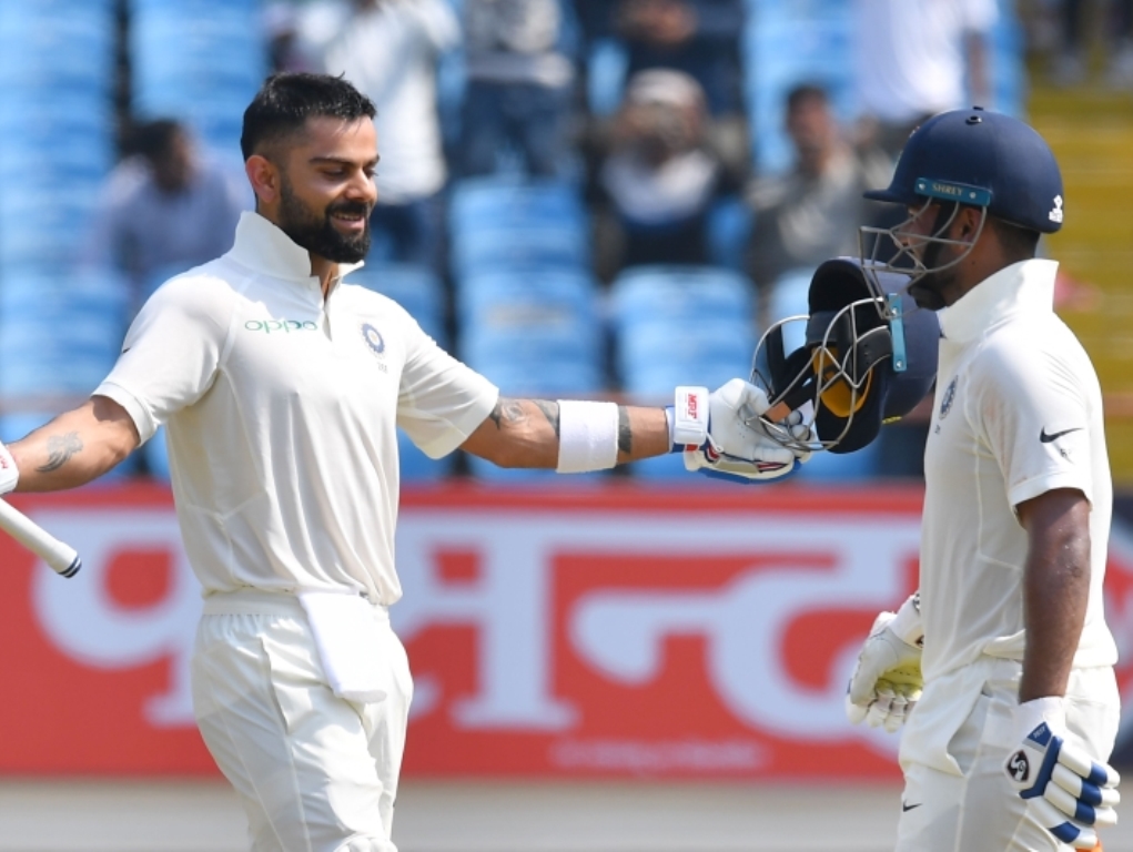 Indian cricket captain Virat Kohli celebrates after reaching his century (100 runs) as teammate Rishabh Pant looks on during the second day's play of the first Test cricket match between India and West Indies at the Saurashtra Cricket Association stadium 