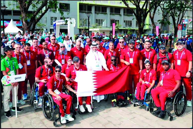 The head of the Qatari mission, Abdulqader Al Mutawa, and team members with Qatari flag at the Olympic village for the Asian Para Games in Jakarta. 